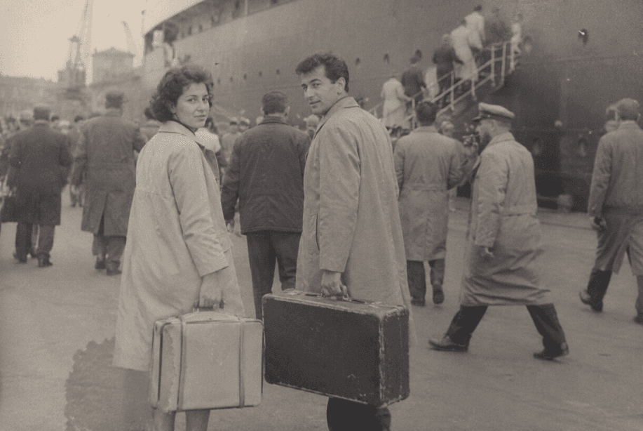 A family group on a quayside beside a moored ship.